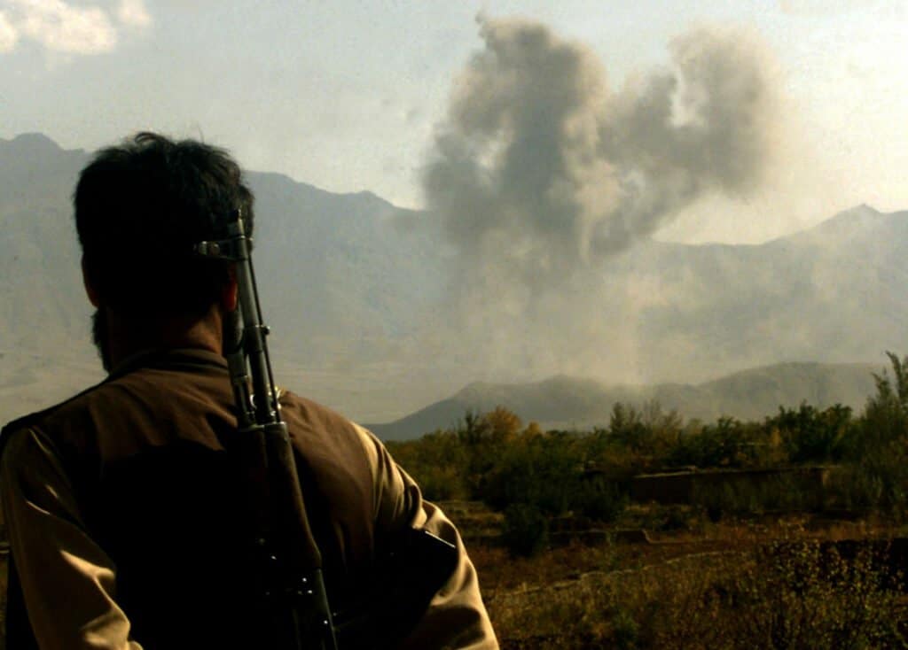 A Northern Alliance fighter watches bombs explode after a US Air Force B-52 struck front line Taliban positions in Tutakhan hill some 25 km North west of the Afghan capital Kabul October 31, 2001. B-52's carpet bombed Taliban positions in this area for the first time since the begining of the US led campaign, pounding the hardline Islamic movement in some of the heaviest strikes of the campaign so far.