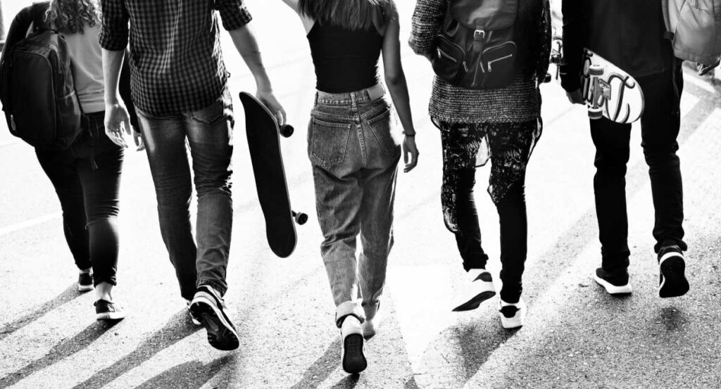 Um grupo de jovens de costas caminhando. A imagem é em preto e branco.