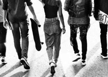 Um grupo de jovens de costas caminhando. A imagem ГѓВ© em preto e branco.