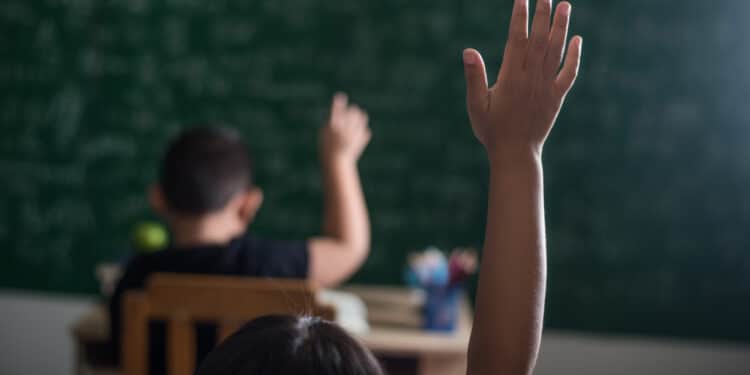 Em primeiro plano vemos uma crianГѓВ§a parda levantando a mГѓВЈo em uma sala de aula do ensino mГѓВ©dio para pesquisa de disparidade racial