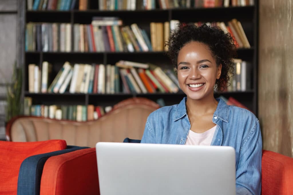 Estudante em uma biblioteca olhando telas em seu laptop. 
