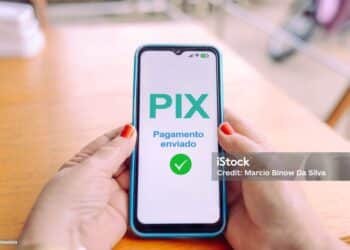 Hands holding a smartphone displaying a payment confirmation via Pix, illustrating the evolution of digital and cashless payment methods