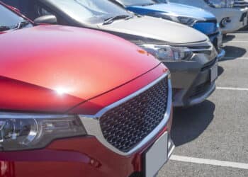 Car parking in asphalt parking lot in a row, front of  cars close up, automobile transportation dealer business concept