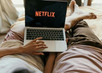 Casal deitado assistindo Netflix no notebook | Fonte : Pexels