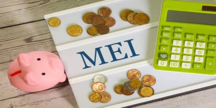 The acronym MEI for Individual Microentrepreneur written on a letter board with a calculator, a piggy bank and Brazilian real coins in the composition. Brazilian economy.