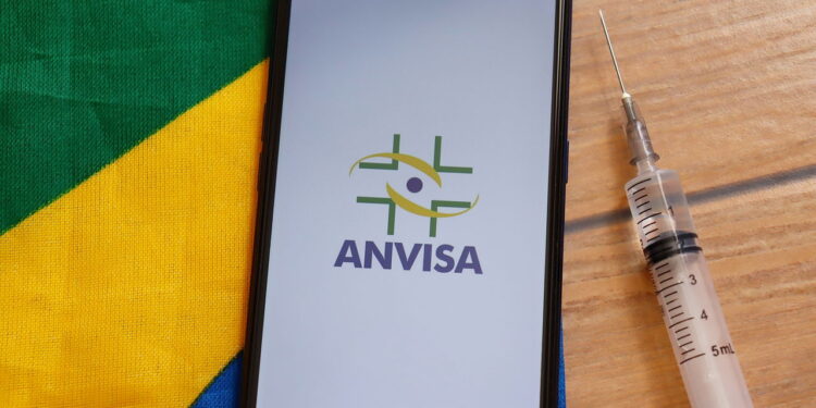 Celular com imagem da Anvisa com seringa ao lado - Créditos: depositphotos.com / BrendaRochaBlossom