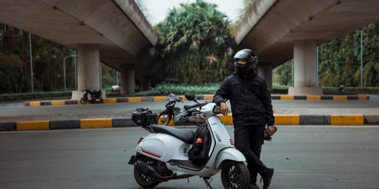 Homem apoiado em sua Scooter | Fonte: Pexels