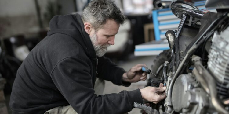 Homem barbudo consertando motocicleta em oficina | Fonte: Pexels