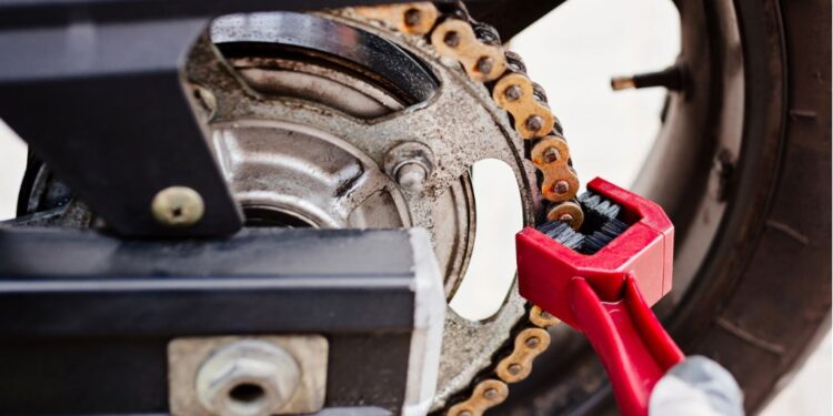 Arrumando corrente de uma moto | Créditos: depositphotos.com / djedzura