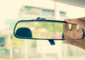Imagem de motorista ajustando retrovisor – Créditos: depositphotos.com / SingHa Wk