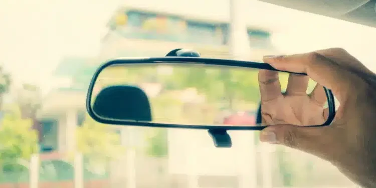 Imagem de motorista ajustando retrovisor – Créditos: depositphotos.com / SingHa Wk