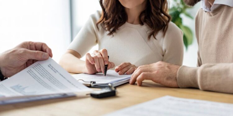 Casal assinando contrato de seguro; proteção financeira.