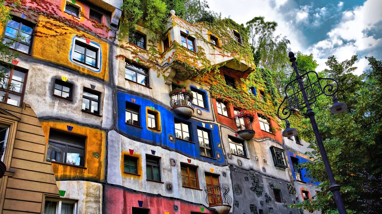 Com suas fachadas coloridas e 250 árvores integradas aos terraços, o edifício de 1985 tornou-se um marco da arquitetura orgânica e ecológica em Viena