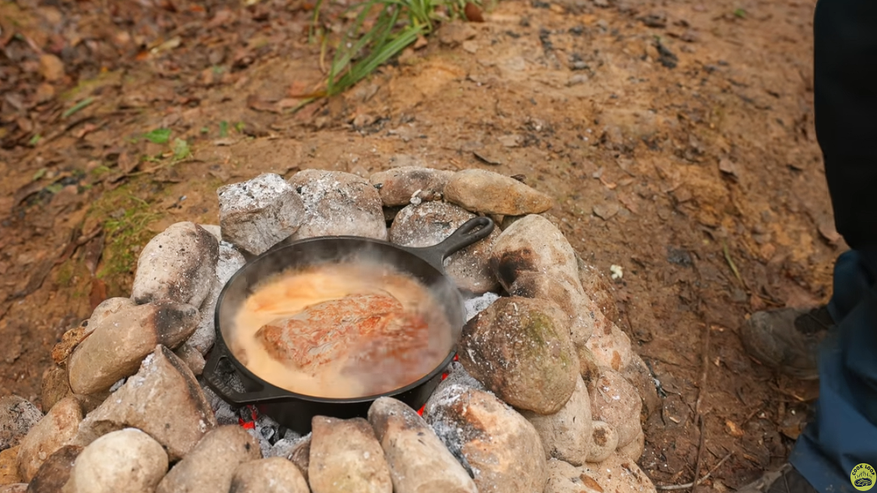 Preparo de sanduíche artesanal na natureza com carne suculenta sobre tábuas e pedras improvisadas