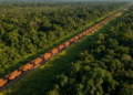 Vista aérea impressionante do trem infinito cortando a floresta amazônica, com vagões de minério sumindo no horizonte
