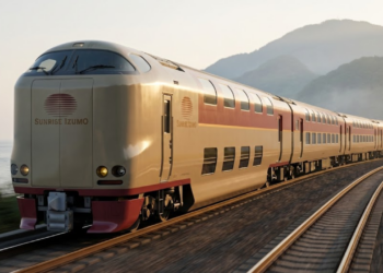 Trem Sunrise Izumo curvando nos trilhos ao amanhecer (Golden Hour), com montanhas e mar ao fundo