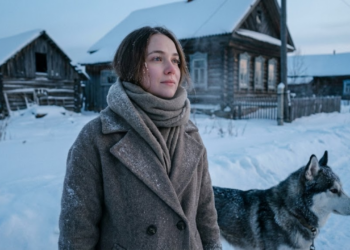 Mulher e seu cão em meio ao azul gelado de uma vila siberiana abandonada.