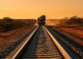 Trilhos da Transnordestina avançando pelo sertão sob a luz do pôr do sol