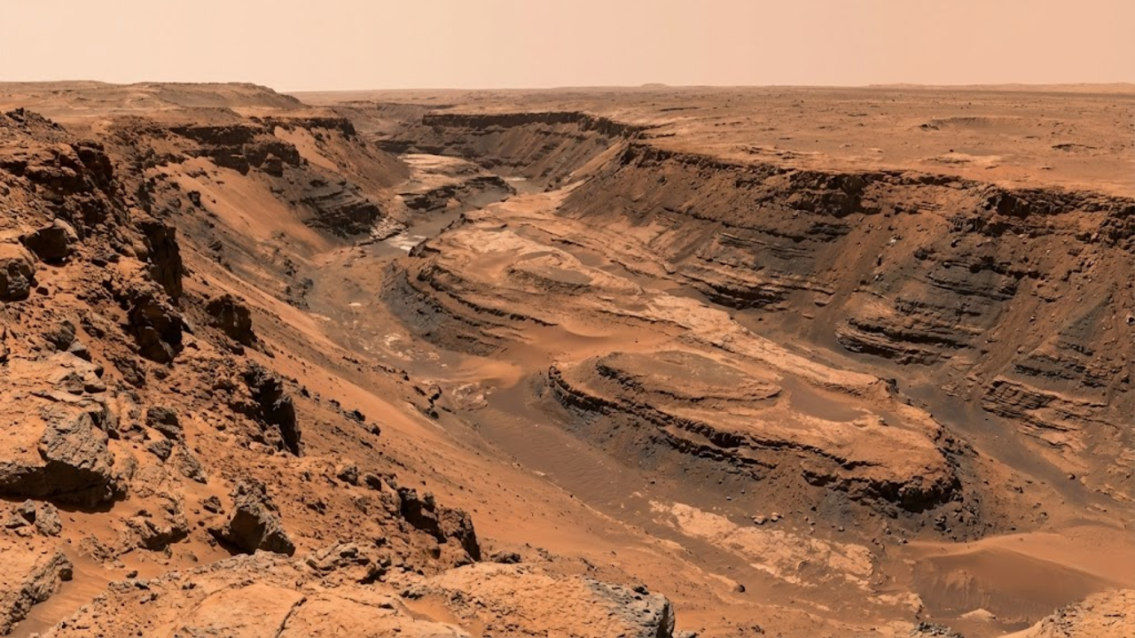 Uma foto ampla da borda do desfiladeiro marciano, mostrando o fundo do canal esculpido e ilhas de pedra moldadas pela água antiga