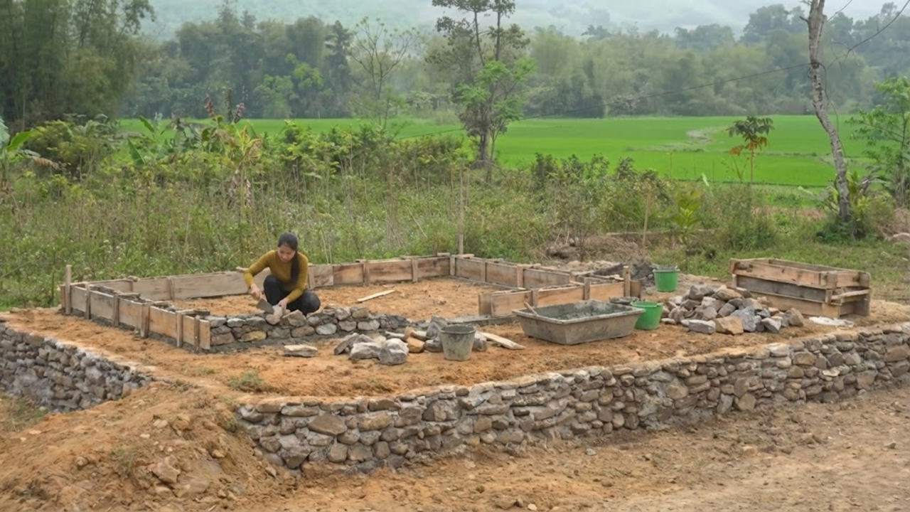 Jovem erguendo paredes de pedra e cimento em projeto de casa autossuficiente e ecológica