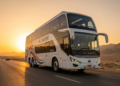 Ônibus de três andares gigante cruzando o deserto ao pôr do sol