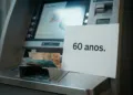 Idoso brasileiro confuso no caixa eletrônico sendo abordado por estranho