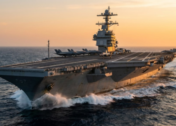 Porta-aviões Gerald R. Ford navegando com caças F-35 sob o pôr do sol.