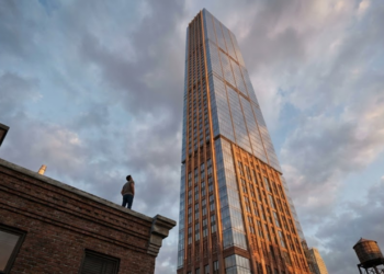 Pessoa maravilhada no telhado olhando para o topo do arranha-céu agulha brilhando ao sol