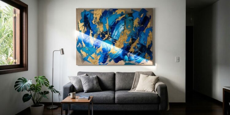 Trocar cinco quadros pequenos por uma peça de arte grande na parede principal reduz a poluição visual e faz a sala parecer até 30% mais larga