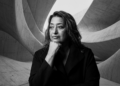 Retrato pensador e intenso de Zaha Hadid em preto e branco.