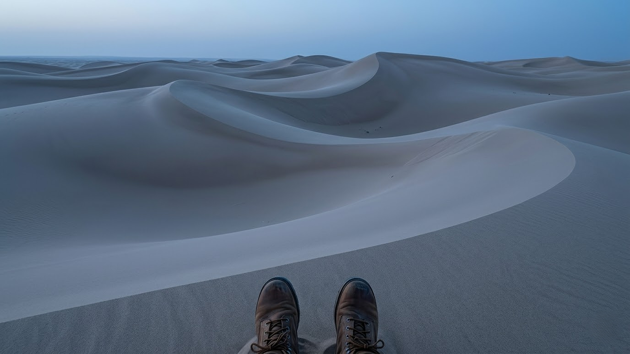 Visão em primeira pessoa observando as curvas orgânicas das dunas do deserto.