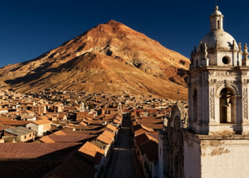 Vista épica do Cerro Rico dominando a cidade colonial de Potosí ao pôr do sol.