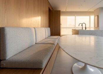 O design contínuo acomoda de 5 a 6 pessoas na mesma metragem que antes abrigava apenas quatro assentos soltos, unindo o cômodo de forma coesa e elegante