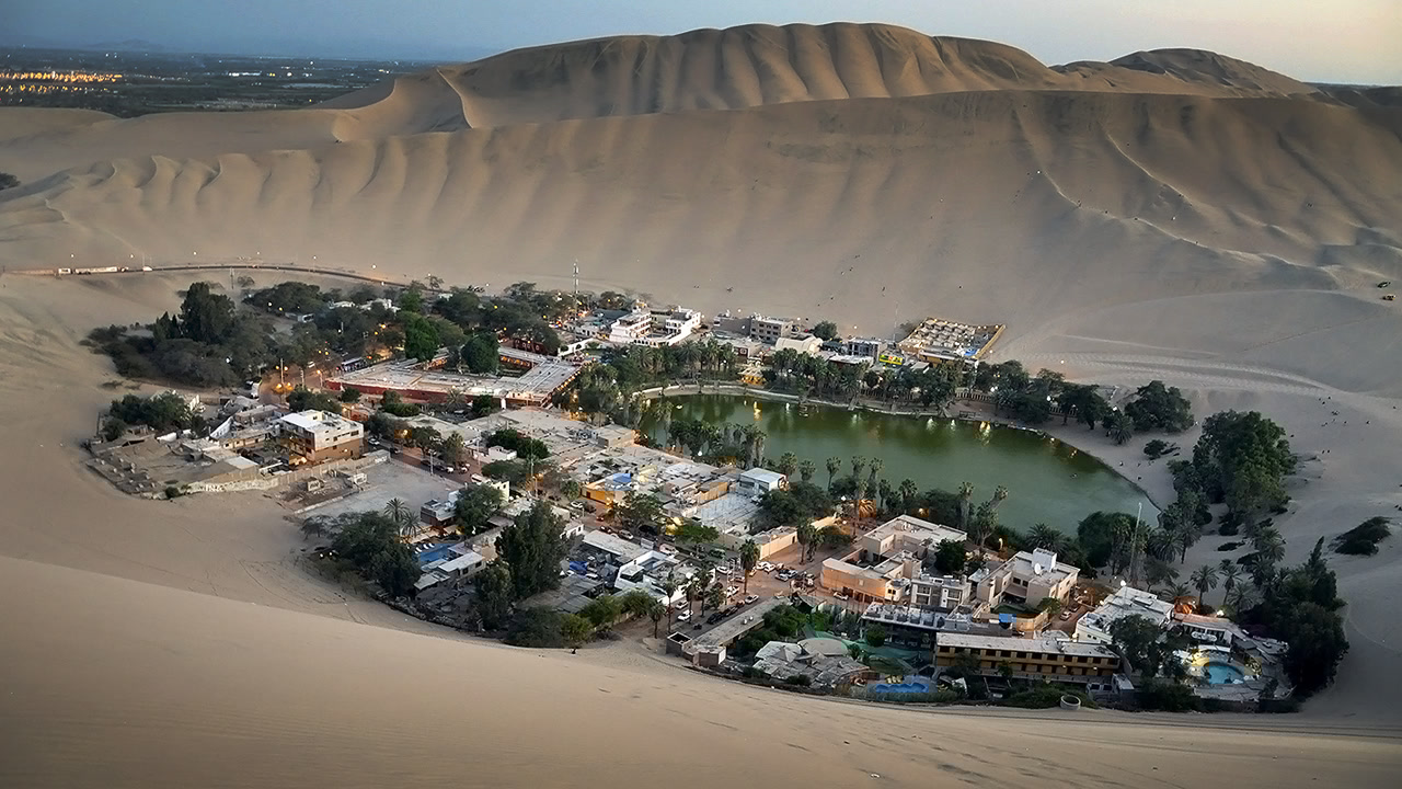 O oásis verdadeiro no meio de dunas de 500 metros de altura que abriga 1 vila isolada em torno de 1 lagoa verde esmeralda