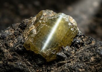 Esqueça o brilho comum, pois este mineral exibe um fenômeno óptico chamado chatoyancy que cria um risco luminoso único no centro