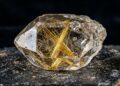 Esqueça o cristal liso, pois este quartzo com agulhas de rutilo de refração 2,62 brilha com filamentos dourados dentro da rocha