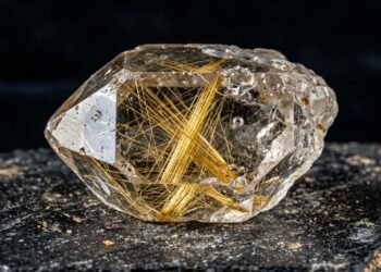 Esqueça o cristal liso, pois este quartzo com agulhas de rutilo de refração 2,62 brilha com filamentos dourados dentro da rocha