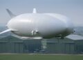 Airlander 10 voando sobre Cardington com hangares históricos ao fundo