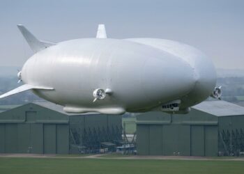 Airlander 10 voando sobre Cardington com hangares históricos ao fundo