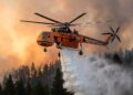 Helicóptero S-64 despeja água sobre incêndio florestal