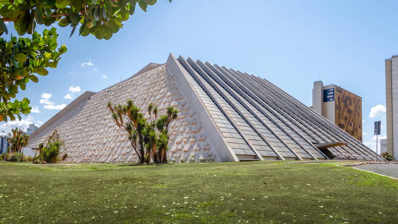Projetado em formato de pirâmide por Oscar Niemeyer, o Teatro Nacional em Brasília exibe fachadas de cubos escultóricos que definem o horizonte