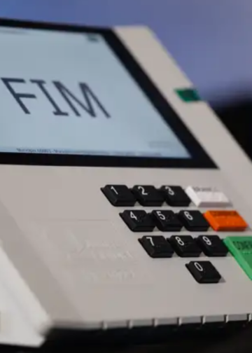 Urna eletrônica em primeiro plano com a palavra "fim" em destaque.