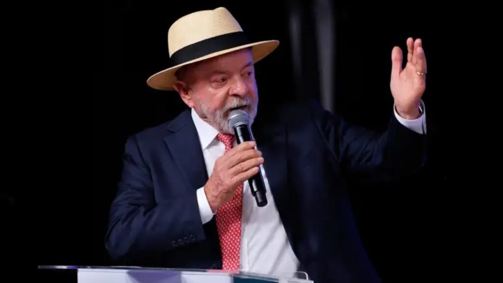 Presidente Luiz Inácio Lula da Silva em primeiro plano, falando no microfone durante discurso em evento.