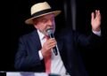 Presidente Luiz Inácio Lula da Silva em primeiro plano, falando no microfone durante discurso em evento.