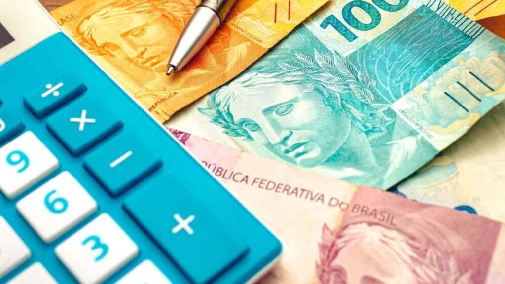Notas de reais e uma calculadora azul no canto esquerdo da imagem