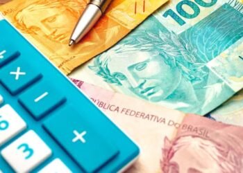 Notas de reais e uma calculadora azul no canto esquerdo da imagem