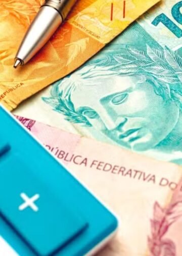 Notas de reais e uma calculadora azul no canto esquerdo da imagem