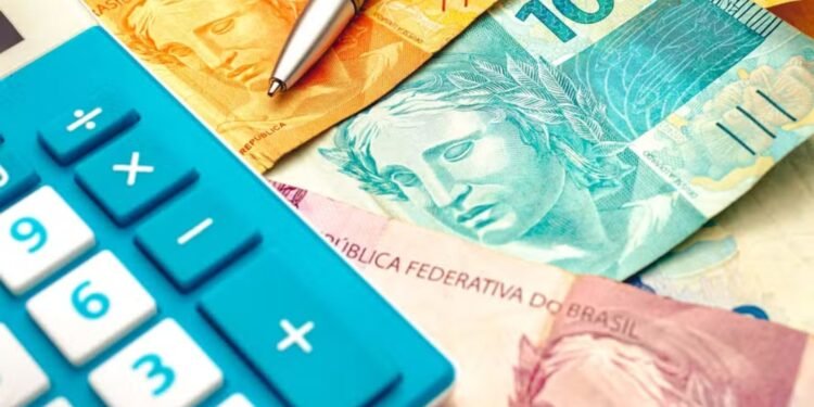 Notas de reais e uma calculadora azul no canto esquerdo da imagem