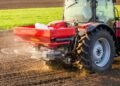 Máquina agrícola jogando fertilizante na plantação.