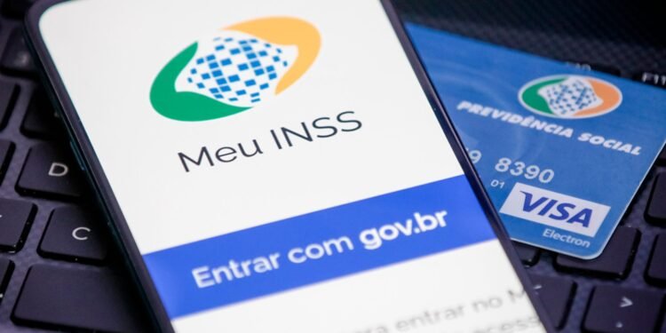 Celular aberto com o aplicativo do MEU INSS e atrás um cartão de benefícios.
